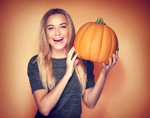 girl holding a pumpkin and smiling