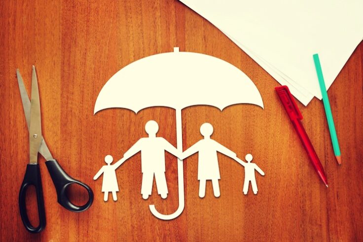 paper family standing under umbrella