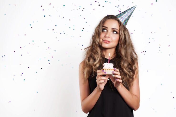 woman celebrating her birthday, holding a cupcake