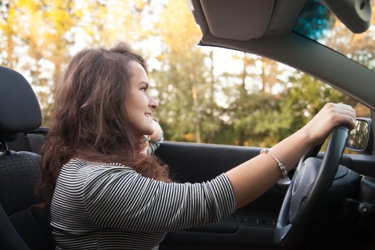 Positive beautiful smiling traveler young woman driving sports car
